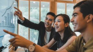 Tiga profesional muda terlihat antusias berdiskusi sambil menunjuk data di layar, menunjukkan kolaborasi dan analisis yang merupakan soft skill mahal bagi anak SI agar cepat jadi leader. (AI)