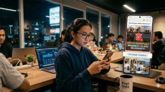 Seorang pengguna memeriksa foto di smartphone sambil bekerja di coworking space, menggambarkan proses penyimpanan dan pemulihan data digital.