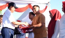 Gubernur Gorontalo Gusnar Ismail (kiri) menyerahkan bendera Merah Putih kepada warga pada pencanangan HUT ke-81 RI di destinasi wisata Danau Perintis, Kabupaten Bone Bolango, Minggu (2/8/2026). (Foto : mcgorontaloprov/Haris)