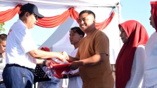 Gubernur Gorontalo Gusnar Ismail (kiri) menyerahkan bendera Merah Putih kepada warga pada pencanangan HUT ke-81 RI di destinasi wisata Danau Perintis, Kabupaten Bone Bolango, Minggu (2/8/2026). (Foto : mcgorontaloprov/Haris)